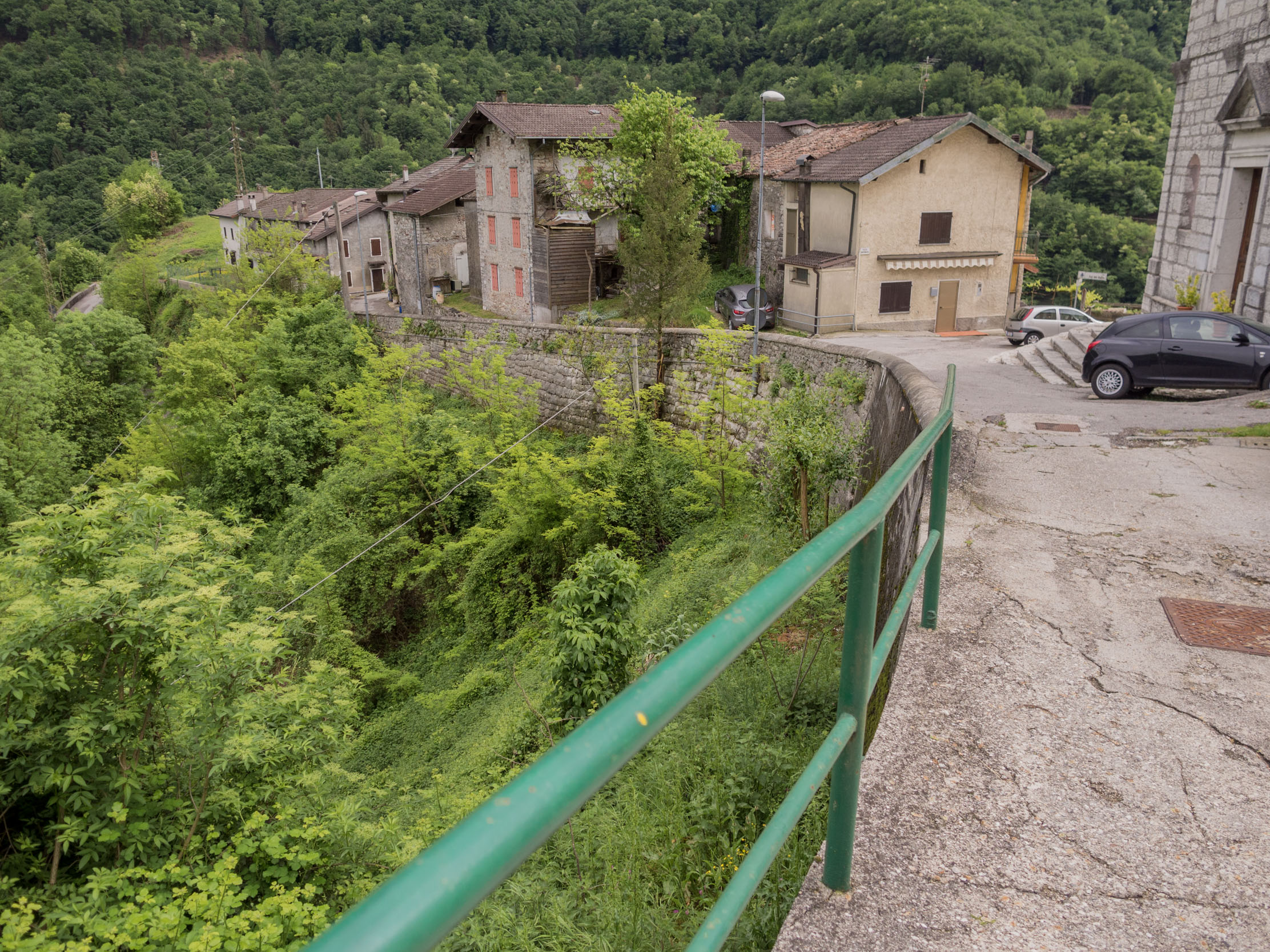 Curving road next to Incino's church with a steep drop to Drio el Col below