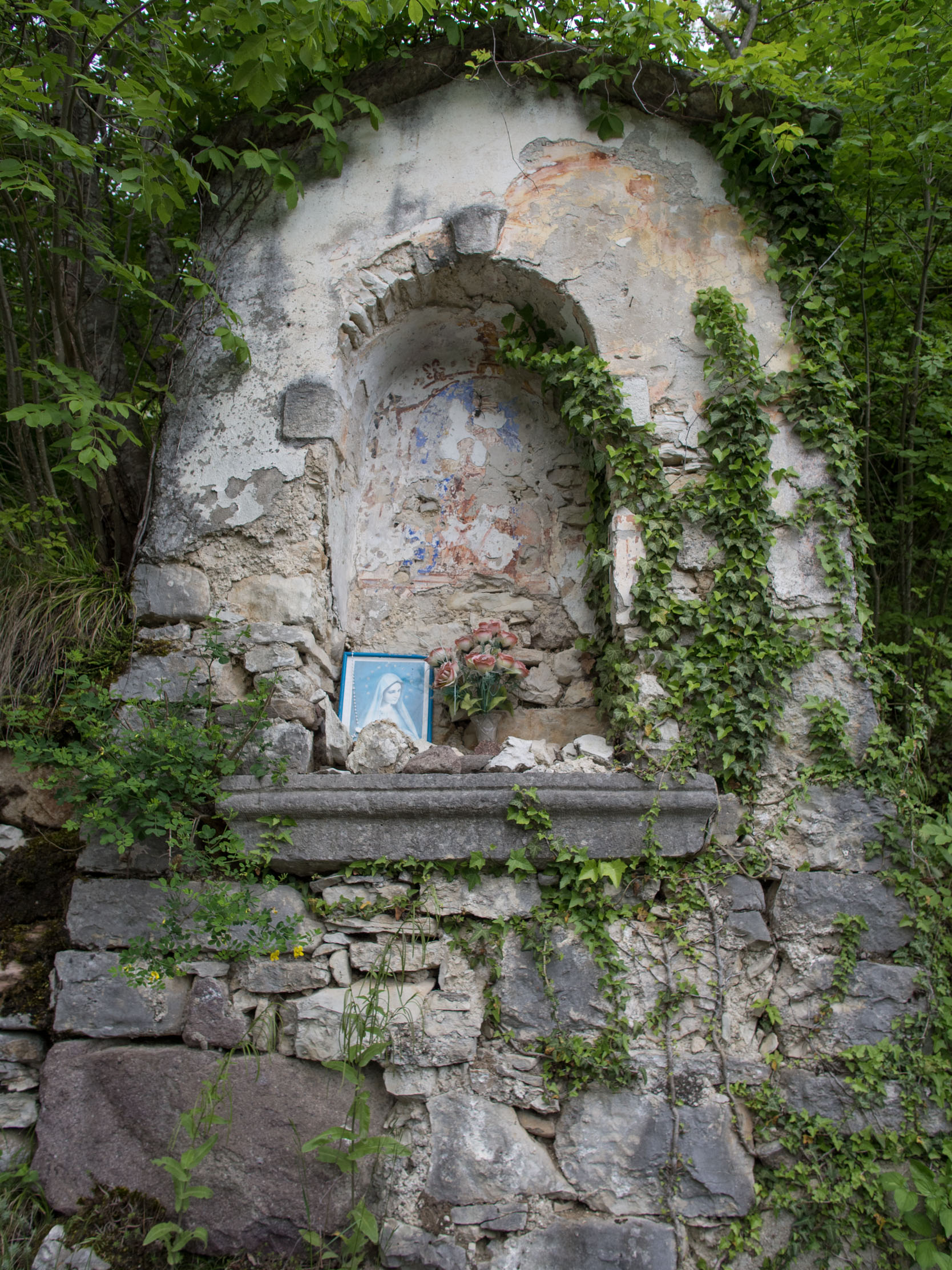 Stone and stucco shrine in poor condition with faded fresco